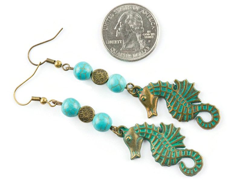 May include: Turquoise and bronze earrings featuring a seahorse charm and turquoise beads. The earrings are approximately the size of a UK 20 pence coin.
