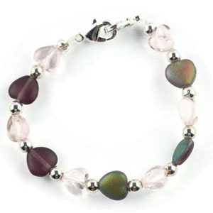 May include: A silver heart charm bracelet with pink, purple, and iridescent heart beads.