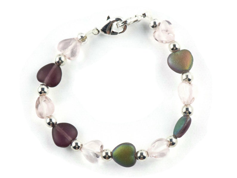 May include: A silver heart charm bracelet with pink, purple, and iridescent heart beads.