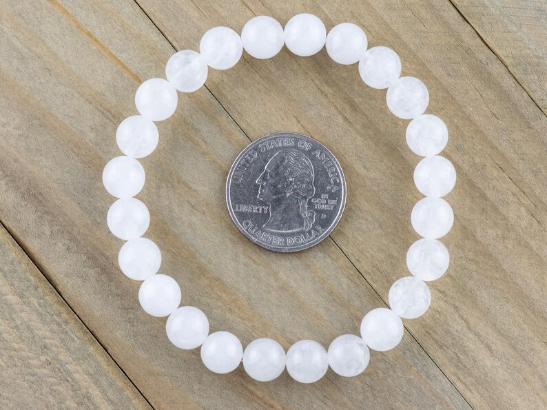 May include: White beaded bracelet made of round, opaque white beads. The bracelet is approximately the size of a US quarter.