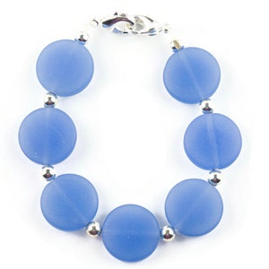 Peut inclure: Un bracelet bleu clair avec des perles rondes et un fermoir argent&eacute;.