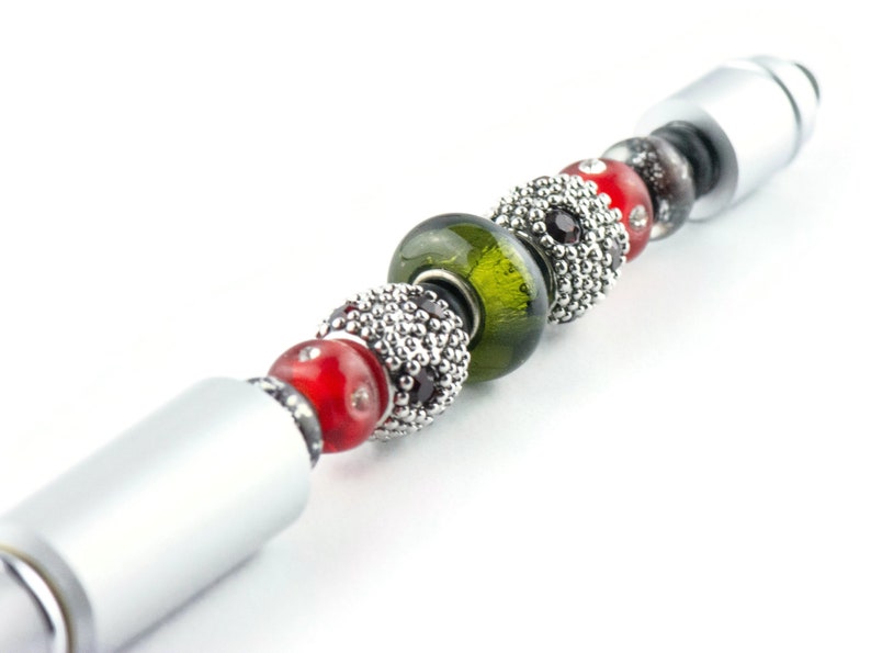 May include: A silver pen with a series of colourful beads, including red, green, and black. The beads are made of glass and metal.