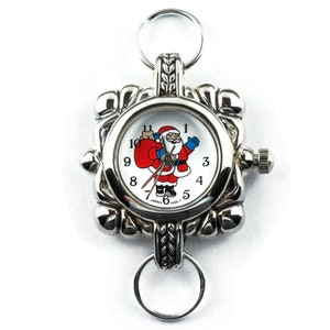 May include: A silver pocket watch with a white face and a Santa Claus design. The watch has a silver chain and a silver clasp.