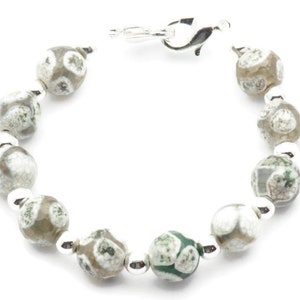 Op de afbeelding: Een zilveren armband met groene en witte agaat kralen. De armband heeft een zilveren sluiting.