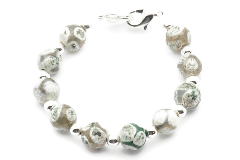 Op de afbeelding: Een zilveren armband met groene en witte agaat kralen. De armband heeft een zilveren sluiting.