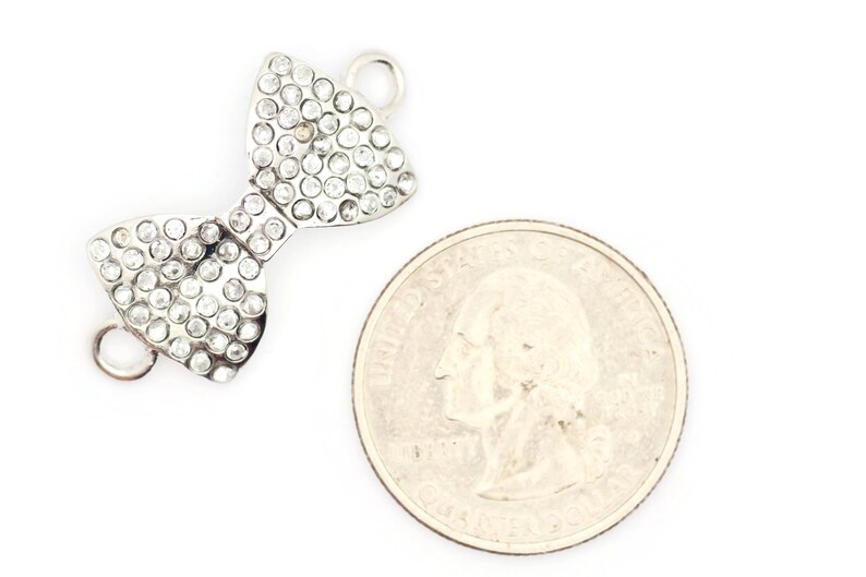 Puede incluir: Encanto de lazo plateado con diamantes de imitaci&oacute;n transparentes. El encanto es aproximadamente del tama&ntilde;o de una moneda de 25 centavos de d&oacute;lar estadounidense.