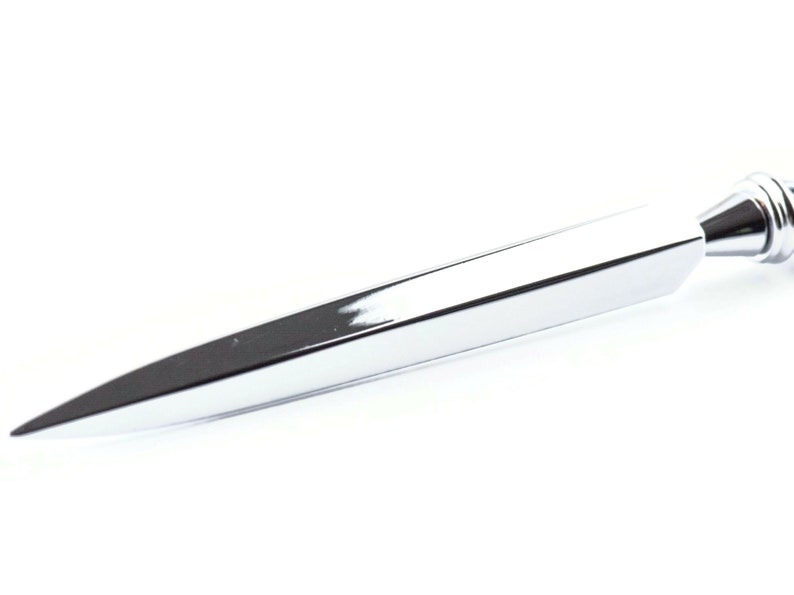May include: A shiny, chrome-plated letter opener with a sharp, pointed blade. The opener has a sleek, modern design and a polished finish, reflecting the light. The handle is rounded and has a decorative design.