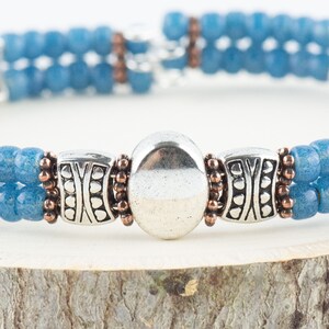 Button and Bows French Blue Cuff Memory Wire Bracelet close up on a wood piece with tree bark edging