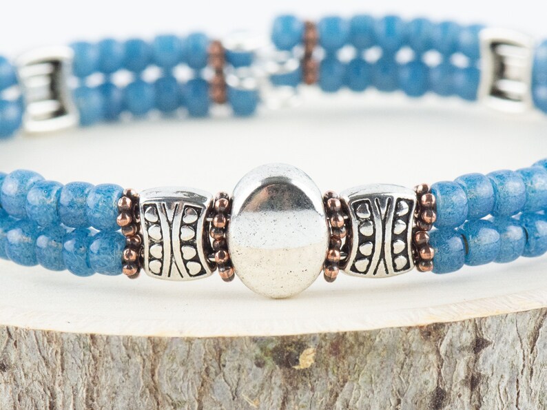 Button and Bows French Blue Cuff Memory Wire Bracelet close up on a wood piece with tree bark edging