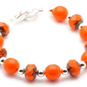 May include: Orange and black glass bead bracelet with a silver clasp.