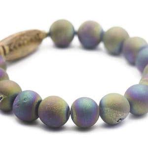 May include: A bracelet made of iridescent agate beads with a wooden accent. The beads are a mix of purple, green, and blue.