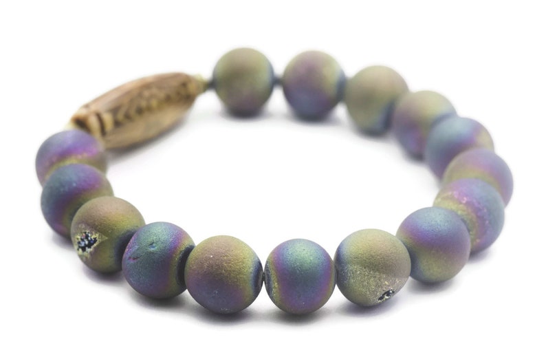 May include: A bracelet made of iridescent agate beads with a wooden accent. The beads are a mix of purple, green, and blue.