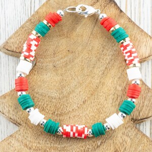 May include: A Christmas-themed bracelet with red, white, and green beads. The bracelet has a silver clasp.