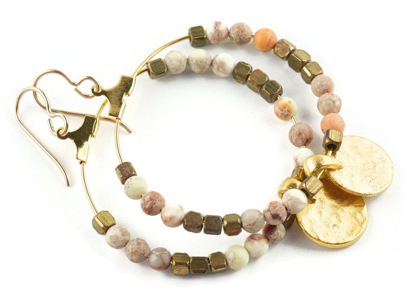 May include: Gold hoop earrings with brown, white, and peach colored beads and two gold charms.