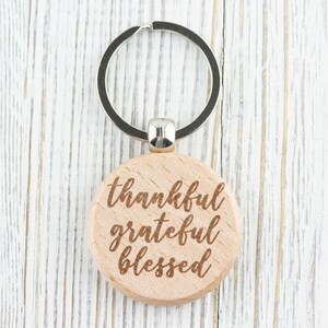 May include: Wooden keychain with a silver ring and the words "thankful grateful blessed" engraved on the front.