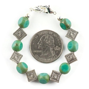 Pu&ograve; includere: Un braccialetto di perline verde turchese con ciondoli quadrati argentati. Il braccialetto &egrave; circa delle dimensioni di una moneta da 25 centesimi di dollaro americano.