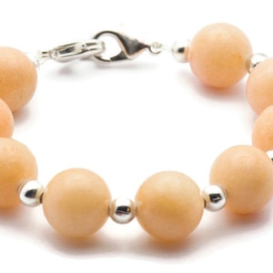 Puede incluir: Un brazalete de piedras preciosas de color melocot&oacute;n con cuentas de plata y un cierre de plata.