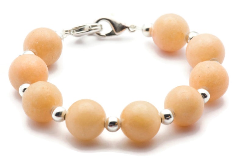 Puede incluir: Un brazalete de piedras preciosas de color melocot&oacute;n con cuentas de plata y un cierre de plata.