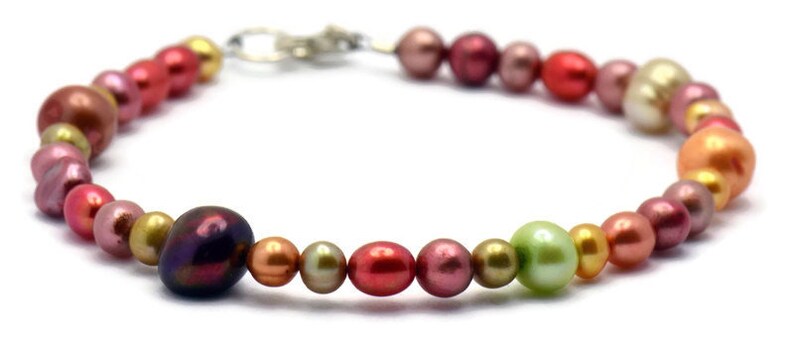 Pu&ograve; includere: Un braccialetto di perle multicolori con una chiusura argentata. Le perle sono in tonalit&agrave; di rosa, rosso, arancio, giallo e verde.