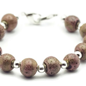 May include: A bracelet made of brown and pink speckled beads with silver accents.