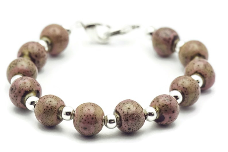 May include: A bracelet made of brown and pink speckled beads with silver accents.