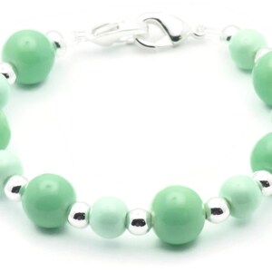 May include: A green and silver beaded bracelet with a silver clasp. The bracelet is made with round beads of varying sizes.