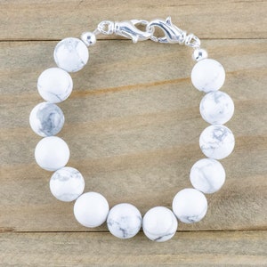 Peut inclure: Un bracelet en perles de howlite blanche avec un fermoir argent&eacute;.