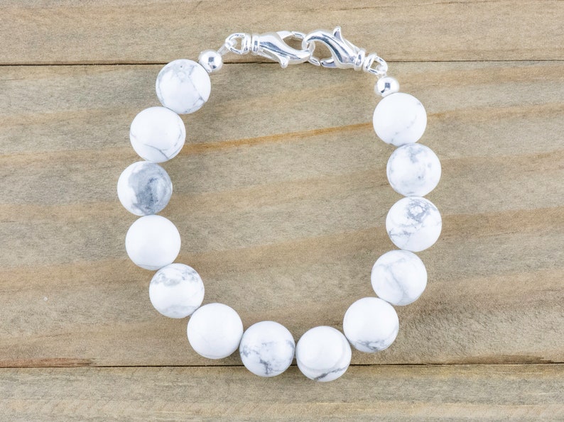 Peut inclure: Un bracelet en perles de howlite blanche avec un fermoir argent&eacute;.