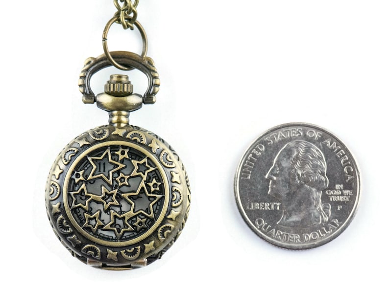 May include: A bronze pocket watch with a star-shaped design on the face. The watch is about the size of a US quarter.