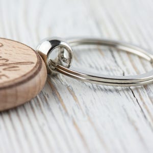 K&ouml;nnte beinhalten: Nahaufnahme eines Holzschl&uuml;sselanh&auml;ngers mit den Worten "Beach Life" eingraviert. Der Schl&uuml;sselanh&auml;nger hat einen silbernen Metallring. Die Holzscheibe ist hellbraun und der Metallring gl&auml;nzend silberfarben.