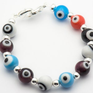 Puede incluir: Un brazalete con cuentas de plata y cuentas de vidrio de colores con dise&ntilde;os de ojo turco. Las cuentas son azules, rojas, negras y blancas.