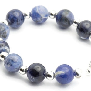 K&ouml;nnte beinhalten: Ein Armband aus blauen und wei&szlig;en Edelsteinen mit silbernen Perlen und einem silbernen Verschluss.