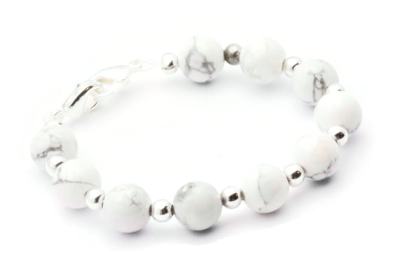 May include: A bracelet featuring white and grey marbled stone beads, interspersed with small silver-coloured beads. The bracelet has a silver clasp and is designed to be worn around the wrist.