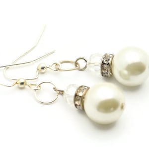 Peut inclure: Une paire de boucles d'oreilles pendantes en argent avec des accents de perles blanches et de cristal.