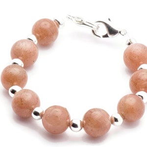 May include: A bracelet made with light brown sunstone beads and silver spacer beads. The bracelet has a silver clasp.