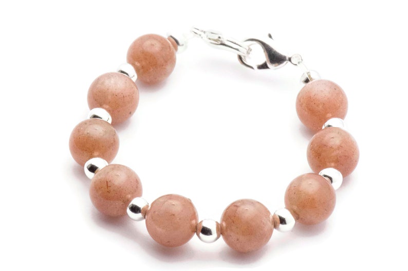 May include: A bracelet made with light brown sunstone beads and silver spacer beads. The bracelet has a silver clasp.