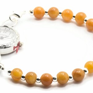 May include: A silver watch with a white face and black Roman numeral markings. The watch is attached to a bracelet made of orange beads and silver spacers.