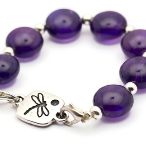 May include: A purple amethyst beaded bracelet with a silver dragonfly charm and a lobster clasp closure.