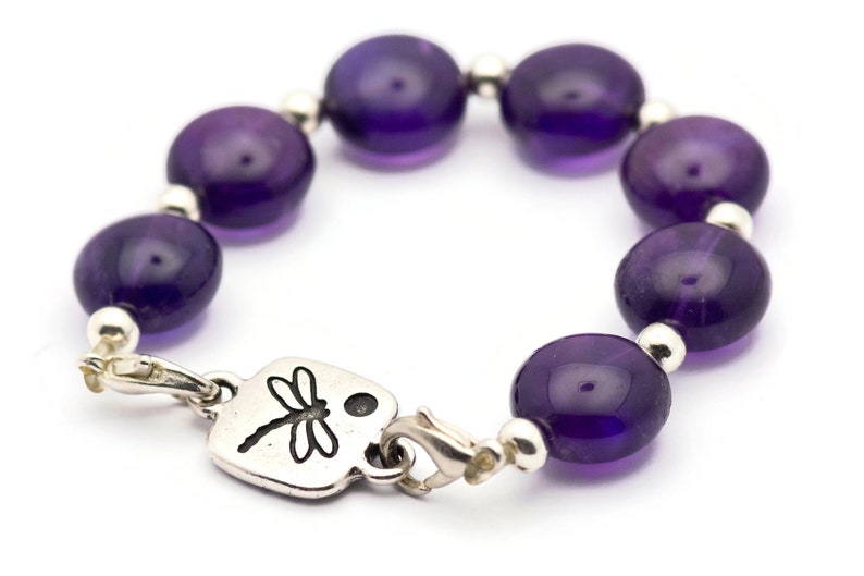 May include: A purple amethyst beaded bracelet with a silver dragonfly charm and a lobster clasp closure.