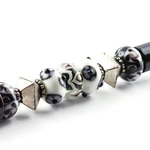 May include: A black pen with a silver and black patterned design. The pen has a black and white patterned cap with silver accents.