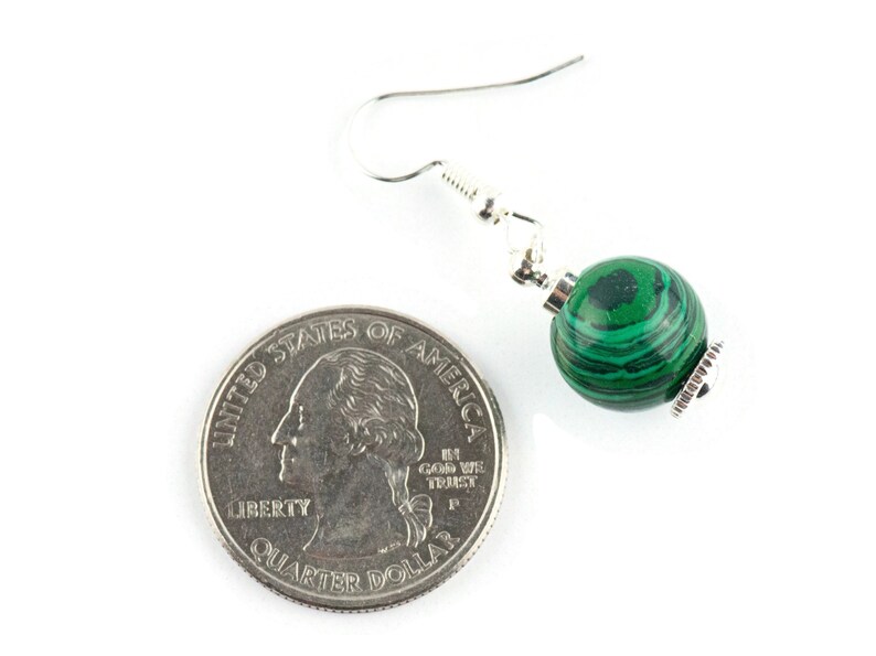 May include: Green malachite gemstone dangle earrings with silver hooks. The earrings are shown next to a US quarter for size reference.