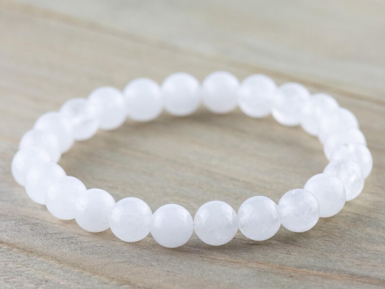 May include: A white gemstone bracelet with round beads. The bracelet is made of natural stones and is designed to be worn on the wrist.