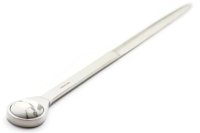 May include: A silver letter opener with a white marble handle. The handle is round and has a smooth surface. The letter opener is approximately 25 cm long.