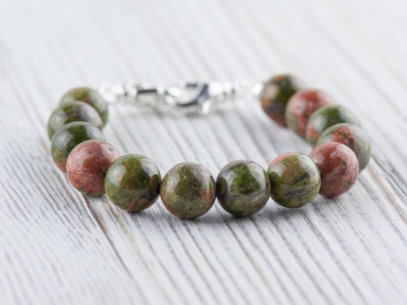 Puede incluir: Un brazalete de piedras preciosas verdes y rojas con un cierre de plata. El brazalete est&aacute; hecho de cuentas redondas y tiene una longitud aproximada de 18 cm.