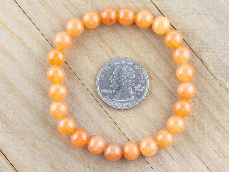 May include: A bracelet made of orange carnelian beads. The bracelet is approximately the size of a US quarter.