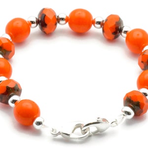 May include: Orange and silver beaded bracelet with a lobster clasp closure.