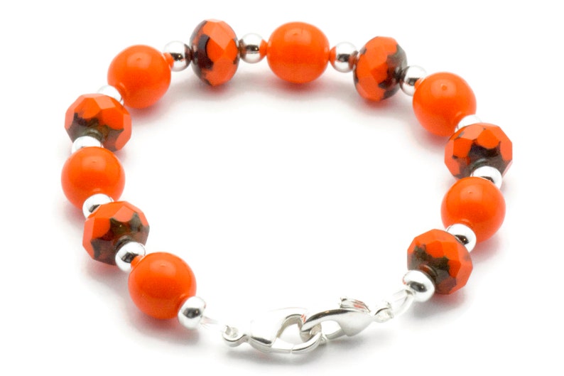 May include: Orange and silver beaded bracelet with a lobster clasp closure.