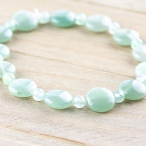 Peut inclure: Un bracelet en pierres pr&eacute;cieuses vert clair avec des perles de forme ovale. Le bracelet est fait de pierres naturelles et est parfait pour un usage quotidien.