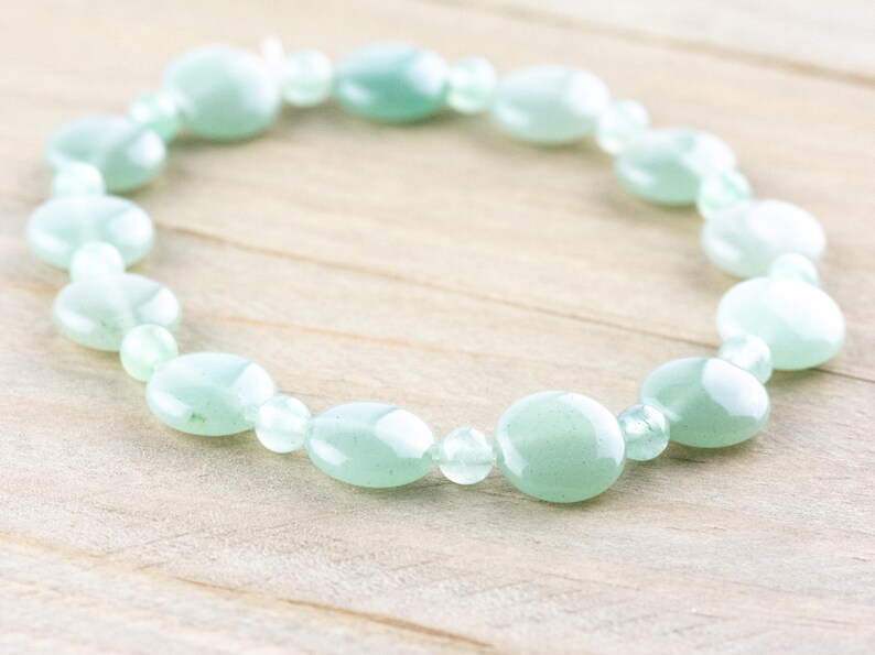 Peut inclure: Un bracelet en pierres pr&eacute;cieuses vert clair avec des perles de forme ovale. Le bracelet est fait de pierres naturelles et est parfait pour un usage quotidien.