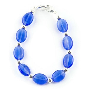 May include: A blue glass bead bracelet with silver accents. The bracelet is made with oval-shaped beads and a silver clasp.